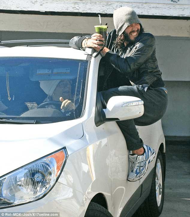 A man hanging on to the side of a car.