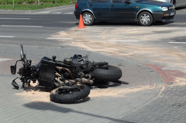 Motorcycle crashed laying flat on the ground.