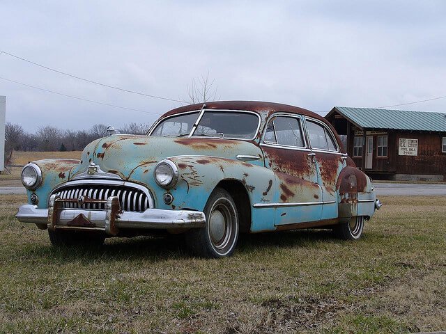 Old patinaed car in a field 